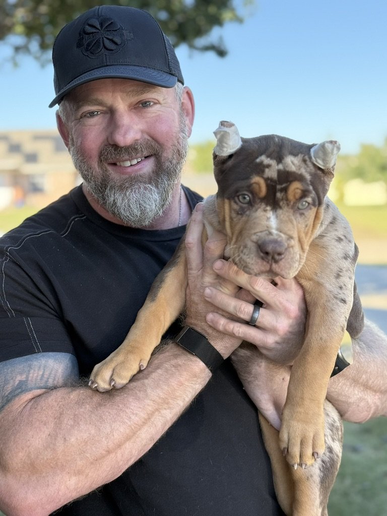 Jake holding Rye as an eight-week-old puppy in a Texas backyard